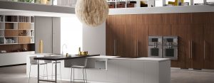 Nogal Sunset con elegantes vetas verticales para los armarios, Fenix NTM® Blanco Malé para los muebles bajos de la isla y Roble Nabuk para la encimera del banco desayuno con duelas, provisto del soporte ajustable Slender.