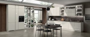 Sistema modular de pared “Fluida” en melamina decorativa Blanco Puro, para separar y conjuntar ambientes contiguos. El detalle de las repisas de cristal combina con armonía con el cristal brillante Blanco Prestige de los frentes de la zona cocina.
